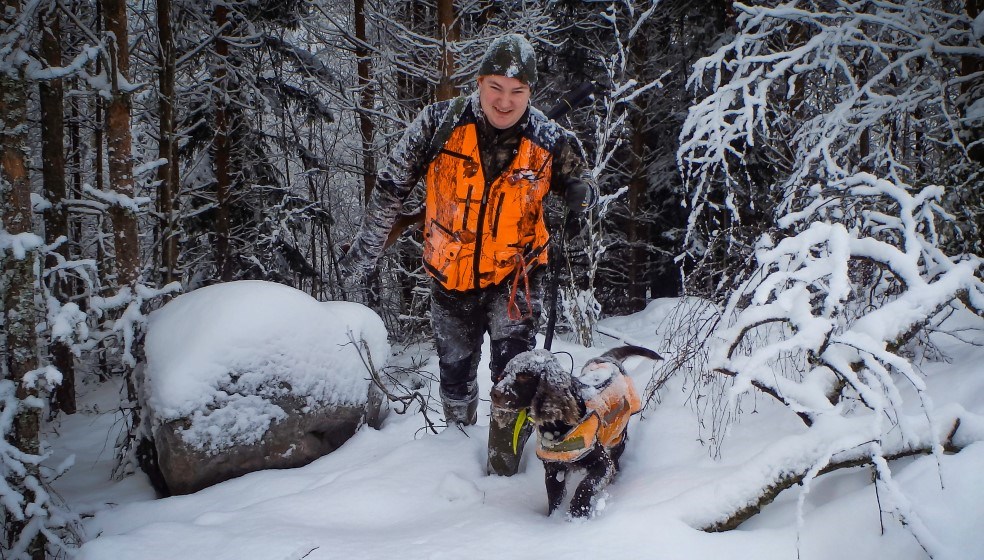 Jägare med hund i skog i snö
